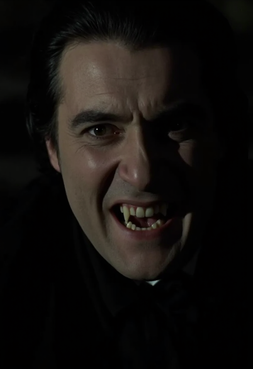 close-up face shot of an aristocratic vampire man sneering showing fangs, face filling the whole frame. Pale skin, dark clothes, dark hair, neutral black background. Low light at night   <lora:hammer-000073:1>