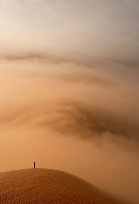 A lone figure dissolving into the shadows of a vast ethereal caramel fog