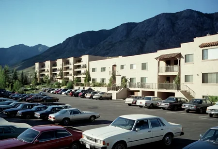 parking lot, cars, condos, mountains, outdoors, highly detailed, 4K, (grainy analog 35mm photo)