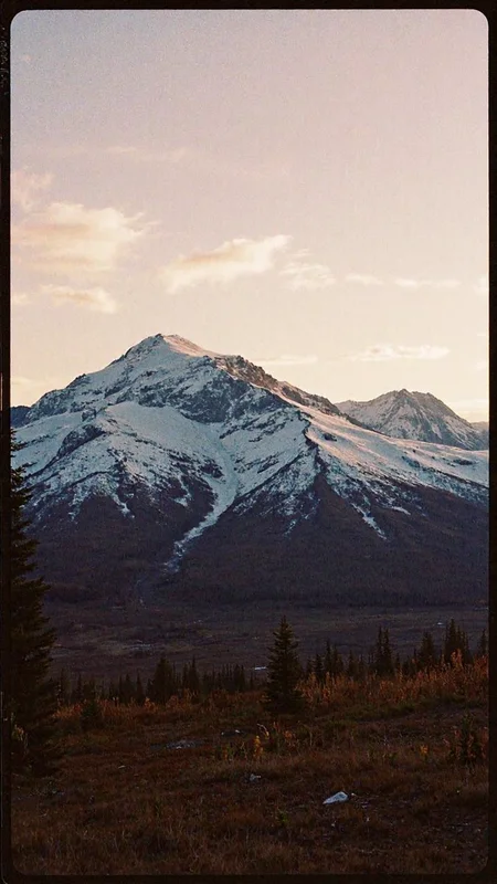 8n8log, Evening photo of an Alaskan mountainscape. Evening, long shadows, dusk <lora:GrainScape_1404698:1> , film photography aesthetic, film grain effect prominent throughout image, grainy film-like textureâââ