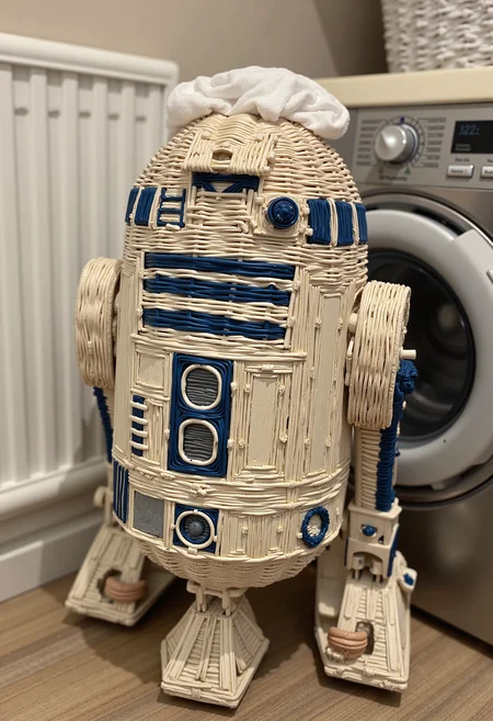wkrstyle r2-d2 from Star Wars, he has unwashed clothes on his head, he is next to the washing machine