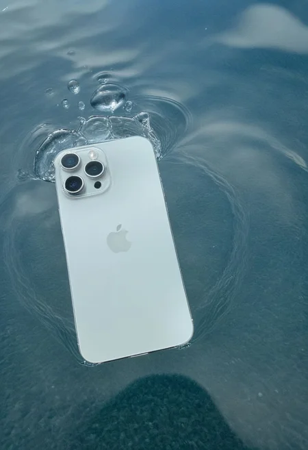 A smartphone with water ripples on its surface and a water droplet suspended above it, against a gradient blue background, suggesting a tranquil and clean environment.