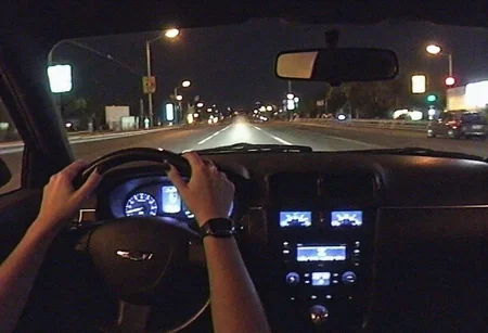 v8s, Dimly lit photo, grungy aesthetic, gritty urban, los angeles city on background, interior of muscle car driving under high speed, amateur quality, nighttime, in motion, smeared background, headlights glowing, noise and grain film, glowing dashboard where speedometer is blurred, rearview mirror, woman's hand with black nailpolish on stearing wheel, first person perspective, pov, wide angle go pro lens