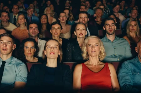 photo of a large group of people sitting in a cinema, many faces,