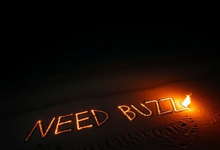 aerial view of tropical desert island beach in night. There is written text on beach sand with fire by a survivor "NEED BUZZ"
