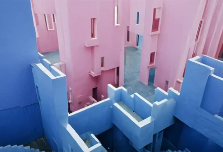 La Muralla Roja by Ricardo Bofill, Postmodern architecture, photograph, pink and blue walls, courtyard, stairs, windows, doorway, maze of stairs, tower, overcrossing, shadows, sea in background, ((maximum detail, supreme quality, 4k, best clarity))