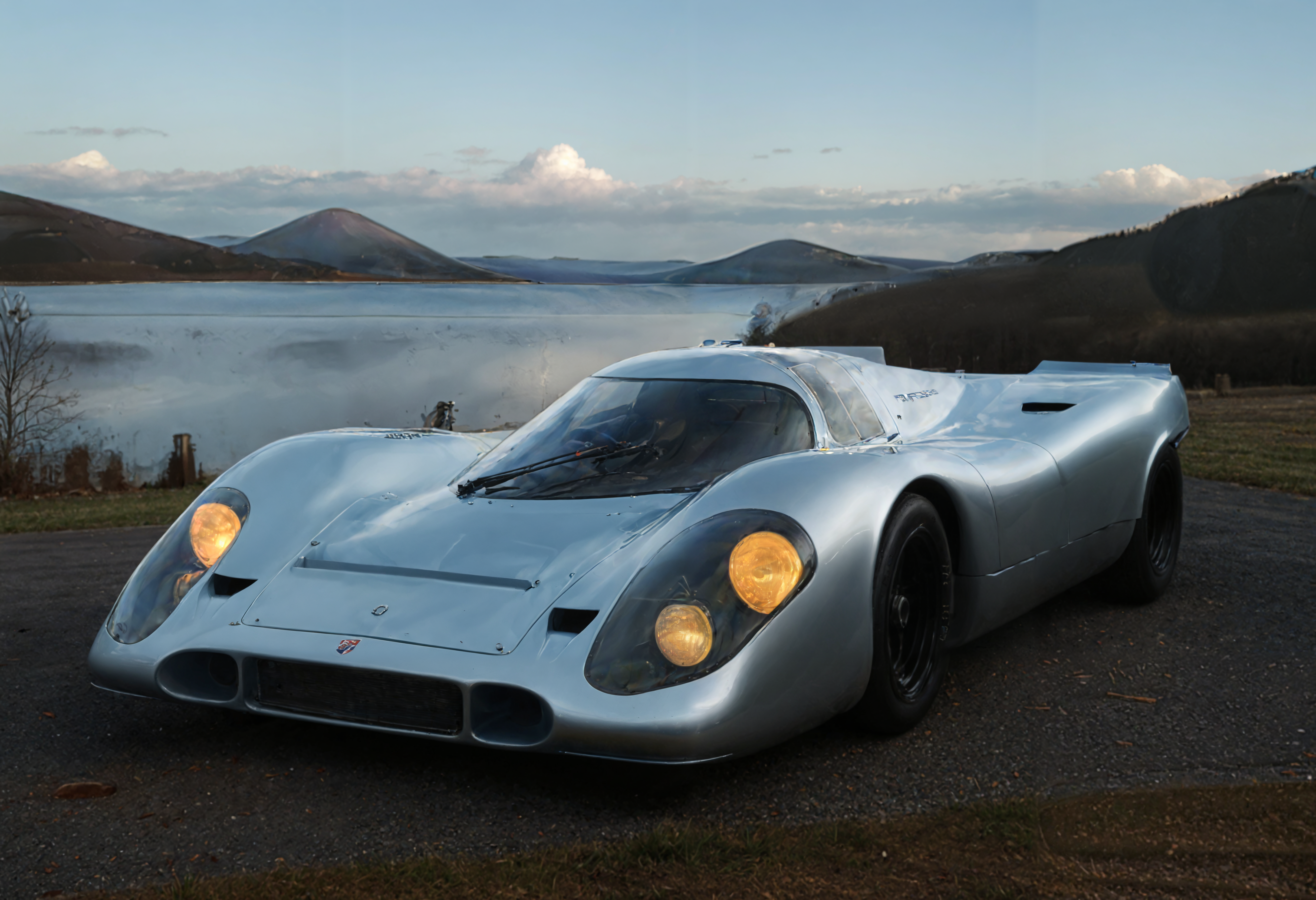 a photograph of a sports car, p0rsche9l7xl,     Clear Blue Skies: Bright, clear skies that often symbolize positivity, openness, and clarity., Silver Blue,  front view , A serene, lakeside cottage at twilight., dark, low-key,   low color saturation, concept art, perfect composition, masterpiece, professional photography, zeiss lens, shot on dslr 64 megapixels, sharp focus, intricately detailed, dramatic, tilt shift, f/32,