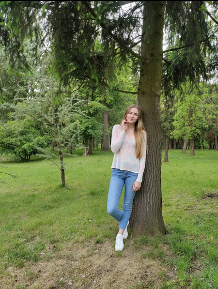 quiet forest clearing on a cloudy day, with tall spruce trees and soft green grass underfoot. In the foreground, a large spruce tree with textured bark and drooping, dark green needles. A young woman with long blonde hair stands beside it, gently touching the bark. She wears a pastel blouse, light blue jeans, and white sneakers. Her expression is calm and thoughtful, as if connecting with the tree. The light is soft and diffused, with a peaceful atmosphere and natural color tones throughout.