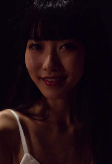 a Korean woman, solo, black hair, long hair, looking at viewer, parted lips, bangs,,indoors,makeup, high detail skin,Spaghetti strap white dress,close-up,smile,dark,Black background