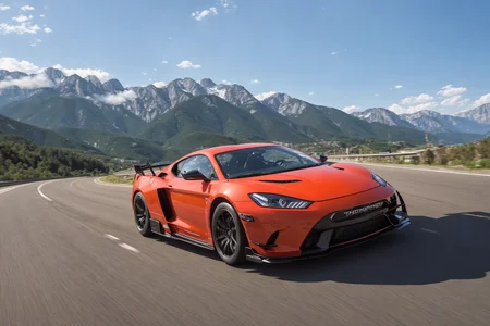 a photo taken of the front of a super-car drifting on a road near mountains at high speeds with smokes coming off the tires, front angle, front point of view, trees in the mountains of the background, ((sharp focus))