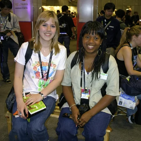 photo of two 25 year old women smiling and sitting on a bench inside E3 convention in 2004 <lora:boring-alpha-v3:1>