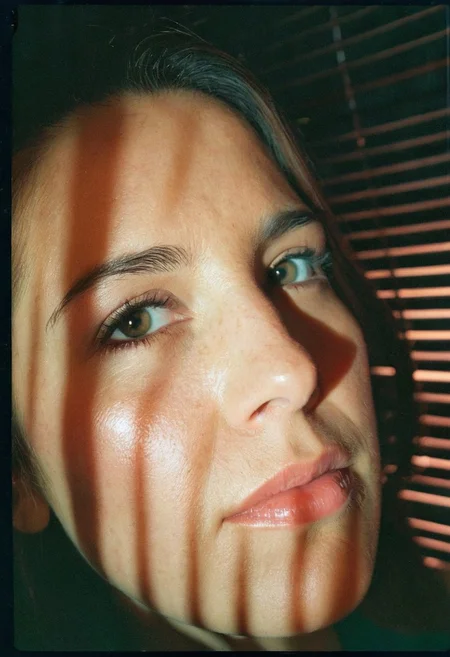 35mm film sample image, Close up shot of a 33 years old woman face, harsh low-key lighting, blinds shadows on her face, high contrast, Grainy, Lomography, lomoChrome, Analog Film, Kodak Ektar 100, Cinematic composition, Rule of thirds