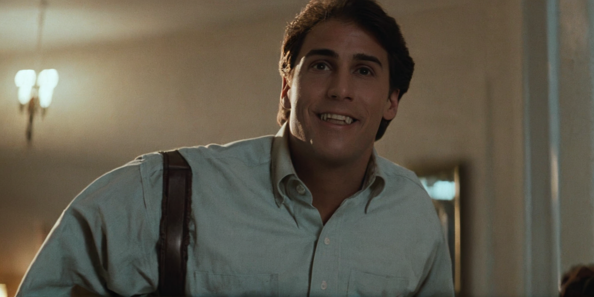 cinematic film still of  <lora:Fright Night 1985 Film Style:1>
Cinematic Wide low angle from below Shot, Film Footage captured by Panavision Cameras and Lenses, Jerry Dandrige a man in a shirt and pants with belt, standing in a room, smiling down at someone with perfect teeth, Fright Night 1985 Film Style, shallow depth of field, vignette, highly detailed, high budget, bokeh, cinemascope, moody, epic, gorgeous, film grain, grainy