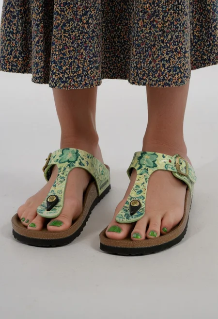 photograph of woman's feet wearing sandals, 1girl, solo, dynamic_pose, simple_background, white_background, gizehonfeet, (green toenail_polish), (close-up:0.5), lower_body, footwear_focus, patterned long_skirt