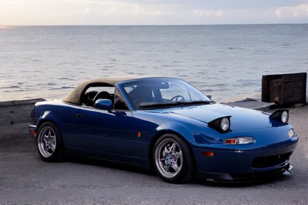 absurdres, ((masterpiece, best quality)),extremely_detailed_wallpaper, illustration, car, bright ,shinny ,shinny sky, ((beautiful detailed sky)) ,(((seaside))),blue water,sunny,sun,morning, cloudy sky, sky,outdoors ,light, cloud, ((backlight)) ,light,sports car,vehicle focus, <lora:MX5NA-000008:0.8>