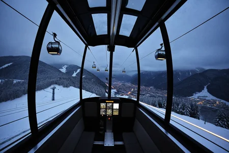 Inside a mountainside cable car gliding above the valley floor where distant hikers trace ridgelines and forests carpet the slopes. At winter night, (light snowfall:1.08) drifts outside, gondola lamps reflect in the glass, and distant ski lights blink on the valley floor.,, Masterpiece,best quality,realistic,HDR, 8K, masterpiece, best_quality, absurdres, ultra-detailed, highly aesthetic,sweeping landscapes, unique perspectives, epic scale, revealing hidden beauty, showcasing vastness, immersive experience, precise compositions, expert piloting, dynamic angles, cinematic storytelling, showcasing natural wonders, aerial exploration