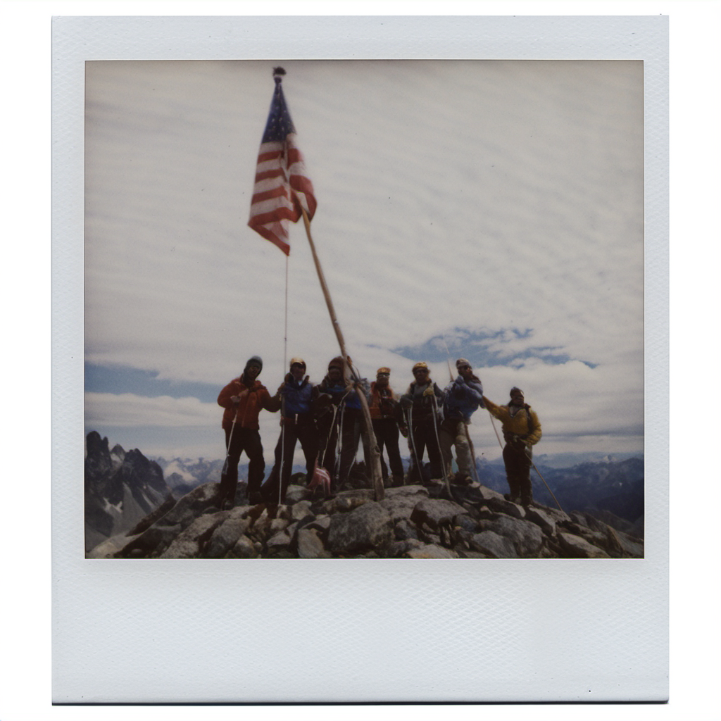 polaroid of A group of mountaineers planting a flag at a summit, clouds swirling below.  <lora:Polaroid_XL:1>