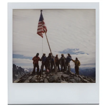 polaroid of A group of mountaineers planting a flag at a summit, clouds swirling below.  <lora:Polaroid_XL:1>