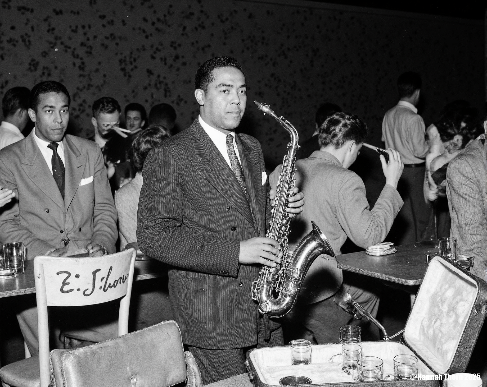 The image is a black and white photograph of the renowned jazz saxophonist, Lester Young, seemingly at a club or bar.    **Description:**  Lester Young is centrally positioned, holding a saxophone. He's dressed in a dark suit and tie, projecting a sophisticated yet relaxed demeanor. The saxophone is partially nestled in its case, which is open and rests on a table. The table is also occupied by what appears to be small glasses or cups and an ashtray.   Behind and to the side of Young are several people, some appear to be patrons of the establishment. One woman is visible, smoking a cigarette; others are partially obscured.  A sign that reads "E.E. Charles" is on the back of a chair behind the table.  The background shows a dark, possibly dimly lit interior with some indistinct wall markings or decorations.  The overall atmosphere appears to be that of a lively yet intimate setting.   **Style:**  The style of the photograph is classic black and white photojournalism or candid portraiture.  The contrast is strong, typical of the era, likely produced from film negatives. The grain is visible, adding to its documentary feel. The composition is fairly straightforward, drawing the viewer's attention immediately to Lester Young. The candid nature of the shot, with other patrons present, makes it seem like a spontaneous capture of a moment rather than a formally posed portrait. The grainy texture and the high contrast between light and shadow are characteristic of mid-20th-century street photography and jazz photography styles.  The slightly blurred background also helps to focus the viewer's eye on Lester Young and his saxophone. <lora:_Flux\Vintage_Jazz-Club.safetensors:1.0:1.0>