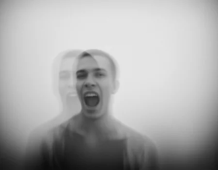 <lora:{blur, }Blur-000018:0.85> blur, This is a black-and-white photograph with a surreal, abstract feel. The image features a blurred, ghostly figure of a man with an open mouth, possibly shouting. The background is a soft gradient, enhancing the ethereal effect. The figure's face is indistinct, adding to the dreamlike quality. The overall mood is haunting and unsettling. . 35mm photograph, film, bokeh, professional, 4k, highly detailed