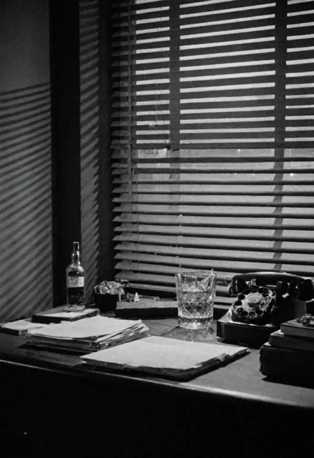 In the 1950s in Chicago, Night, interior of a private detective's office, desk on a bottle of Whiskey, cigarette smoke and little light coming through the blinds on the window. Captured on a 35mm camera, black and white, classic film.
inside