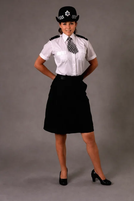 a young woman, <lora:ConstableUniform:0.8> constableuniform, uniform, hat badge, headwear, black constable hat, police uniform, white collared shirt, white shirt, black and white checkerboard necktie, checkerboard necktie, short sleeves, black skirt, black footwear, In a photo studio, 2 shirt pockets, breast pockets, hands on hips