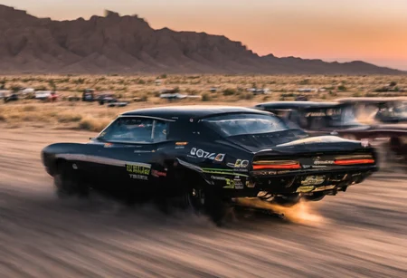 Creates an ultra detailed and realistic image taken by a drone, wide angle, of a race between 2 custom cars, created with parts from many muscle cars, with aerodynamic lines from 1972. The cars have tinted black windows. It is captured in motion with motion blur at full speed through a desert, daylight. Race between 2 cars. The photograph is captured with an Arri Alexa camera, with a zoom lens.
. <lora:Vintage Muscle Car SDXL:1>