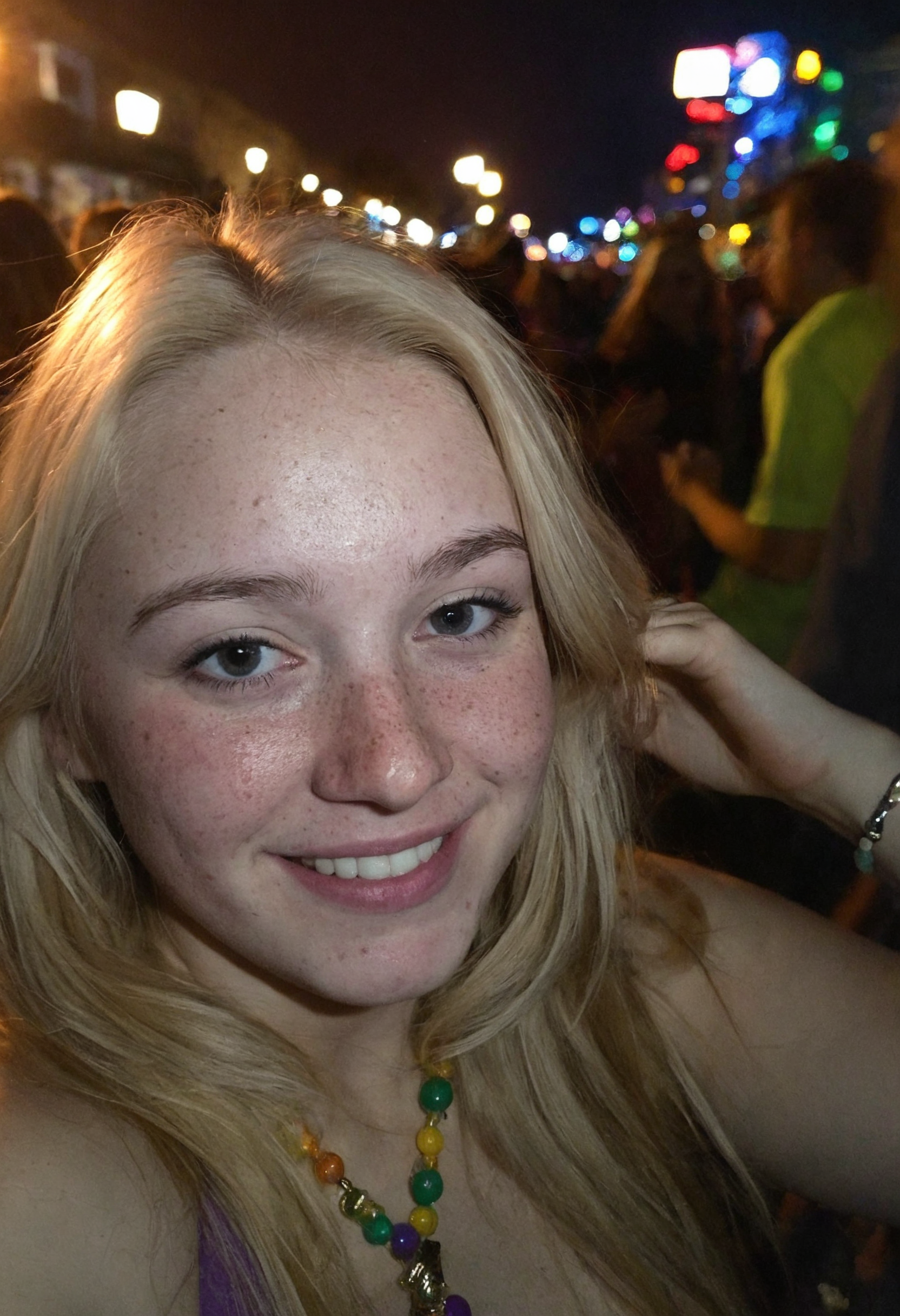 Amateur cellphone photography capturing a cute and attractive young woman with blonde hair at Mardi Gras during a stunning sunset. The scene is vibrant with the festive atmosphere of the parade, colorful beads, and lively crowds in the background. The woman has a playful smirk on her face, exuding confidence and charm, with subtle freckles (freckles:0.2) adding a touch of natural beauty. The photo is taken with a Samsung Galaxy in challenging lighting conditionsâpoor lighting, low light, and underexposedâresulting in a high-contrast image with deep shadows and bright highlights. The composition emphasizes the woman as the focal point, with the warm hues of the sunset casting a golden glow on her features, while the surrounding environment remains moody and atmospheric. The imperfections in the photo, such as graininess and slight blur, add to the raw, authentic feel of amateur photography.