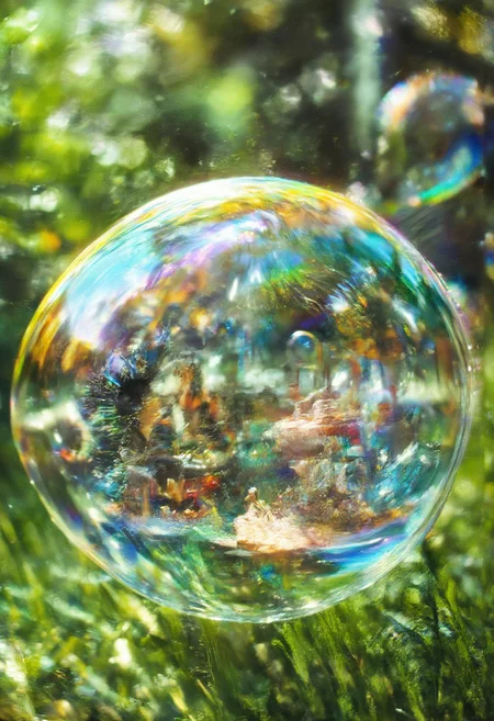 Improved cinematic photo, 35mm photograph, film, professional, 4k, highly detailed, aidmaMJ6.1,
A floating soap bubble encasing a miniature carnival,
The bubble is large and perfectly spherical, with its surface glimmering in the sunlight, displaying a spectrum of vibrant rainbow colors. Inside the bubble, a lively miniature carnival is in full swing, complete with a tiny Ferris wheel, a carousel with colorful horses, and food stands adorned with glowing string lights. Tiny figures can be seen enjoying the rides, their cheerful movement adding life to the scene.
The bubble floats gently above a grassy meadow dotted with wildflowers, the background blurred into a dreamy bokeh of soft greens and yellows. Sunlight streams through the bubble, casting prismatic reflections on the grass below and highlighting the intricate details of the carnival within.
The composition feels playful and surreal, blending the fragile, ephemeral beauty of the bubble with the joyous, vibrant energy of the miniature world inside. It evokes a sense of wonder and nostalgia, capturing the magic of fleeting moments suspended in time.