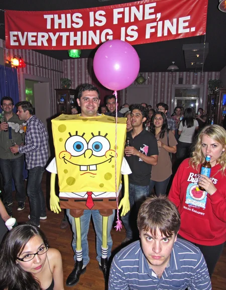 In a wide shot of a night club, a man dressed as the grumpy character resembling SpongeBob is holding a balloon. Above him, a banner reads: âTHIS IS FINE. EVERYTHING IS FINE.â People drinking happily while he stands there, clearly not having it <lora:amateurphoto-v6-forcu:0.8>