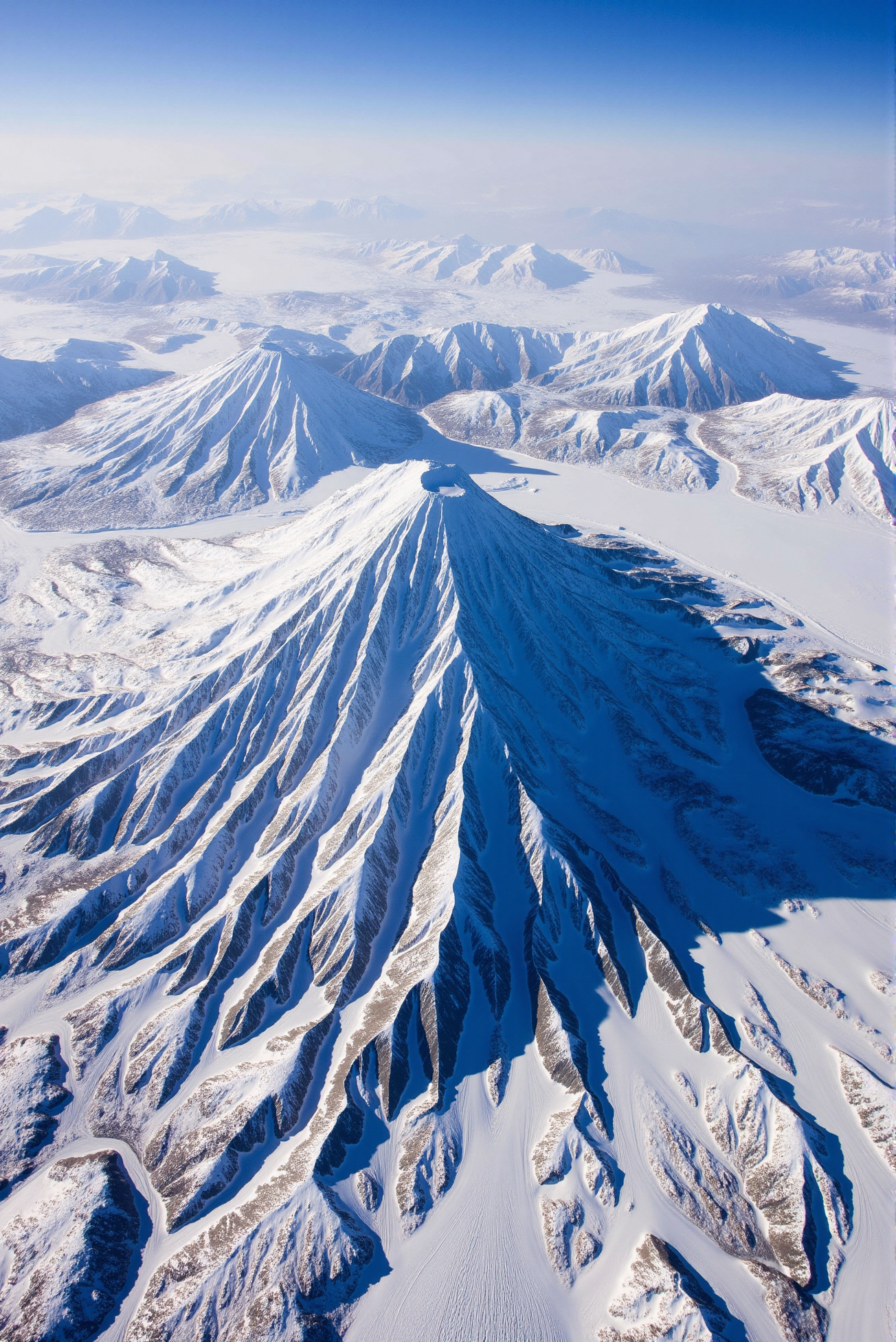 <lora:Ice_Desert_style:0.8> IceDesert style.
A towering conical stratovolcano rises dramatically from a windswept tundra of ice, its flanks carved by deep ravines and long lava scars now filled with gleaming snow. The surrounding landscape stretches into a complex network of snowbound ridges and valleys, each layered in intricate relief with eroded textures and frozen channels. Captured from high-altitude with a sweeping diagonal composition, the scene combines the dynamic geometry of volcanic formation with the soft abstraction of glacial surfaces. The peak casts a massive, angular shadow across the lowlands, enhancing contrast and providing dramatic chiaroscuro balance. The sky above fades from icy blue at the horizon to a muted steel tone near the zenith, emphasizing atmospheric depth. A landscape of ancient upheaval suspended in silence, where fire-forged earth meets the still breath of winter.