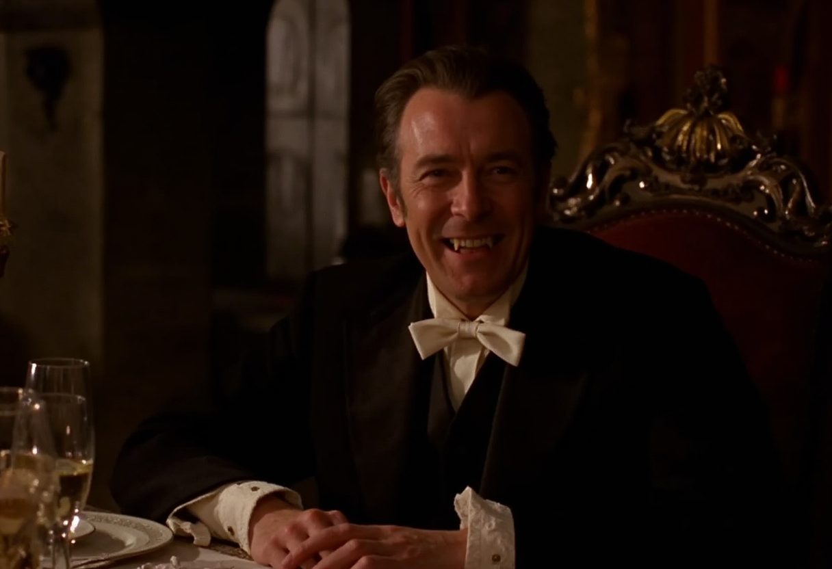 medium shot of a middle-aged aristocratic vampire man sitting at a rich banquet table in a gothic castle, smiling showing fangs. pale skin, dark victorian suit. soft warm light at night <lora:hammer-000073:1>