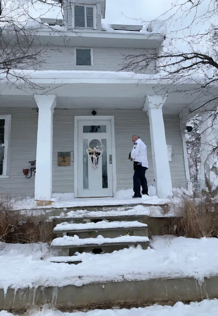 Stable_Yogis_SD1.5_Positives, patherpcook Stands in front of a House, Male, Strong, Flexing, Snow on head, Toga, Pondering, White house, Siding, walkway, driveway,