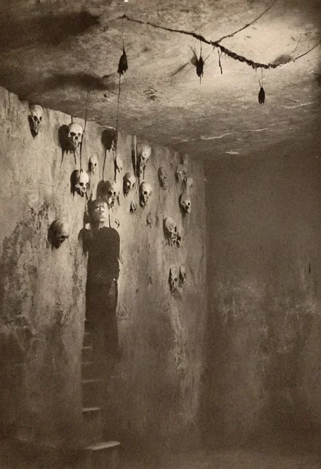 <lora Sairento Hiru style:0.8>, antique photo, eerie atmosphere, creepy man, cave, descent into madness, lovecraft horror, walls made of skulls, one bat hanging from the ceiling, <lora:Antique_Photo:1.2>