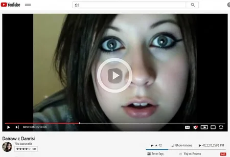 aesthetic2000s, youtube webpage, classic old YouTube window interface, young woman on video, close-up, dark hair, heavy eyeliner, webcam video, online video, social media icons, play button overlay, text overlay, username Danrisi, pixelated, low resolution, internet meme, early 2000s, facial expression, vlogger, nostalgic video, web 2.0 design, rating system, social sharing buttons, grunge aesthetic