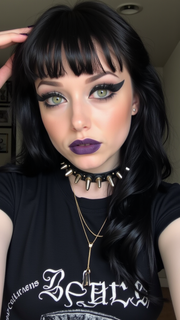 A close-up selfie of a goth woman with piercing green eyes, framed by heavy black eyeliner. She wears a spiked choker and a black band t-shirt, her lips painted a deep purple as she holds the camera slightly above her, goth Girl