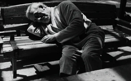<lora:StreetPhotography_pony_v1:1> street photography, black and white,street photography \(genre\), photorealism \(style\), an old man is sleeping on a bench, score_9, score_6_up, score_7_up