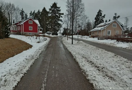 shit_cm_shot, photograph, winter scene, overcast sky, rural road, two houses, left house beige with white trim, right house red with white trim, snow patches on ground, trees without leaves, power lines, road wet, leading lines, low angle, natural lighting,