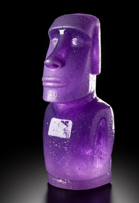 epic photography of A small-scale replica of the Moai statue from Easter Island, meticulously carved from luminous, sparkling amethyst crystals, displayed as a museum specimen. The statue captures the iconic elongated features and stoic expression of the original, with the translucent purple hues of the amethyst glowing under soft, focused lighting. Set against a solid black background, the lighting highlights the crystalline texture and smooth contours of the sculpture. The composition is clean and minimalist, styled like a professional museum catalog photograph, showcasing the mystical allure of this legendary figure.