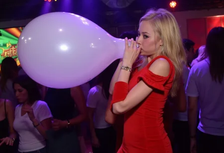 1girl, photograph, blowing white balloon, nightclub, red party dress, looking at viewer