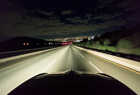 Dimly lit photo, grungy aesthetic, gritty urban, los angeles city on background, pontiac firebird trans am 1978 driving under high speed, amateur quality, nighttime, in motion, smeared background, headlights glowing, noise and grain film, 