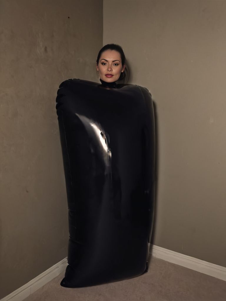 woman in shiny black infltltx sack, standing against wall, dark room, small room, closet door, dark, moody, dim, amateur photo,  <lora:infltltx:1>