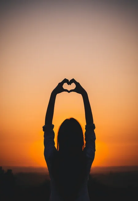 sunset, silhouette, woman, heart shape, hand gesture, warm colors, outdoor, dusk, sky, creative pose, backlit, soft focus, landscape, golden hour, tranquility, leisure activity, nature, serene, orange tones, casual attire