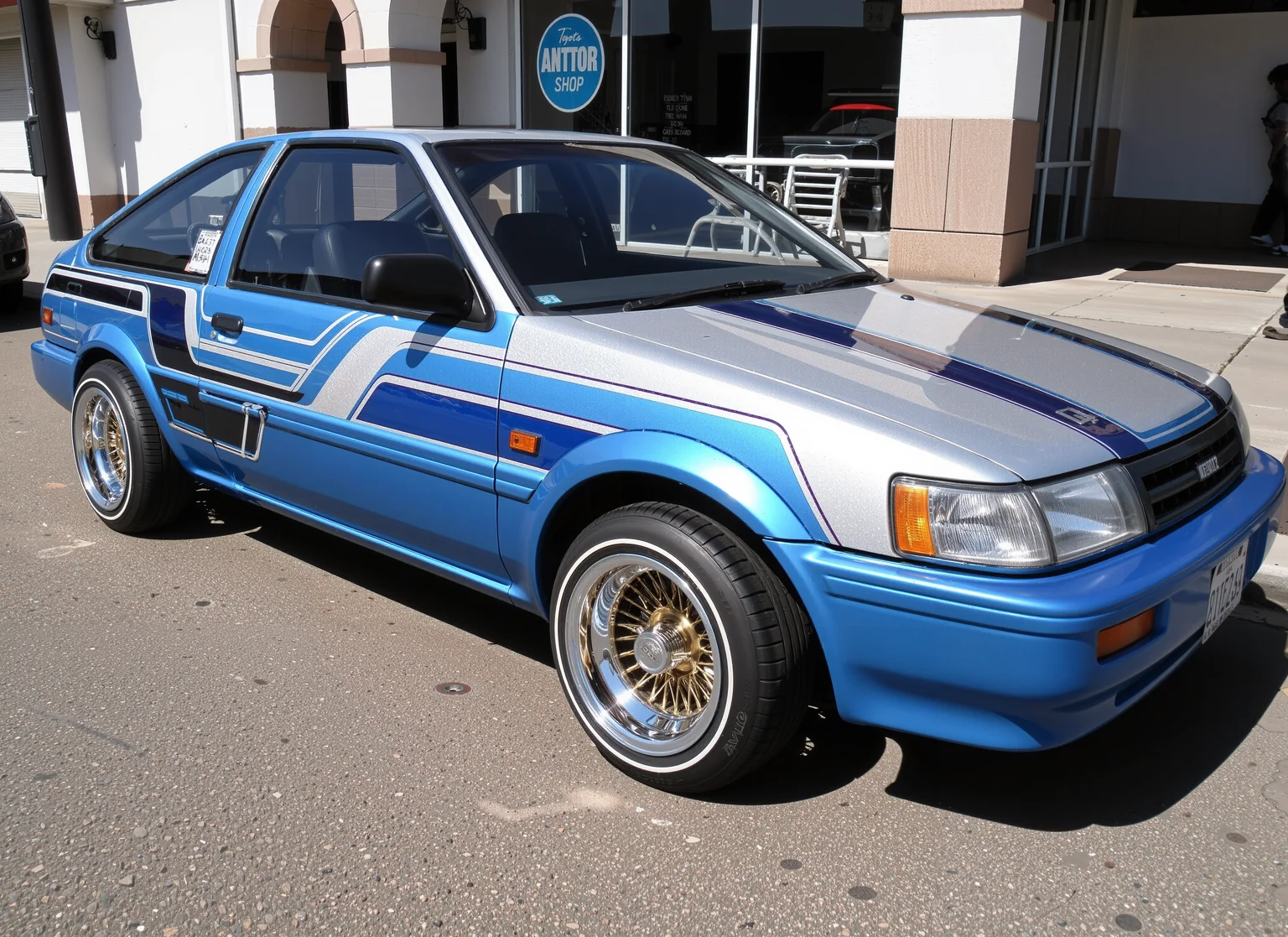 Toyota Corolla Levin AE86 lowrider, chromaflair metalflake paint with blue and white straight line designs on it, white sidewall tires, gold wire wheels, in a los angeles street <lora:lowrider:1> <lora:Toyota_Corolla_Levin_AE86:1>
