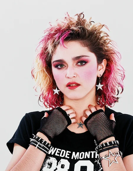 Madonna a woman with wavy mess fluffy updo hair with pink tips, blush, dark eyebrown, dark eyeliner and mascara and red lipstick, long star earrings, 80's bracelet, wearing a black t-shirt and gloves, punk bracelet, against a white background.