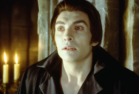 cinematic ultra close-up of a vampire man with pale skin sitting in a stone sarcophagus, eyes wide open, gothic crypt, cobwebs, candles, dramatic chiaroscuro, creepy atmosphere <lora:h4mm3r:0.8>