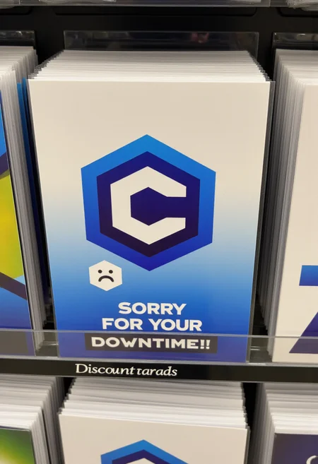 <lora:Greeting_Card_Designer_FLUX:0.8> <lora:civitaiLogoFlux:0.9>
The image is a photograph of a humorous greeting card displayed on a shelf in a store. The card features a civitaiLogo with the text "Sorry for your downtime!" and a sad face.
The background of the card is a gradient of blue and white, giving it a technical computer-like atmosphere.
The section the card is in is titled "Discount cards"