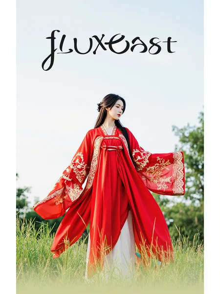This is a clear, Hanfu style photo. In the photo, a woman dressed in a red Hanfu stands on the grass. Her clothes are vibrant with golden patterns. Her hair falls gently over her shoulders, looking smooth and shiny. She looks into the distance, seemingly lost in thought. Her expression is calm, giving a sense of tranquility.
There is a prominent artistic font above the picture, which reads' fluxEast 'in English