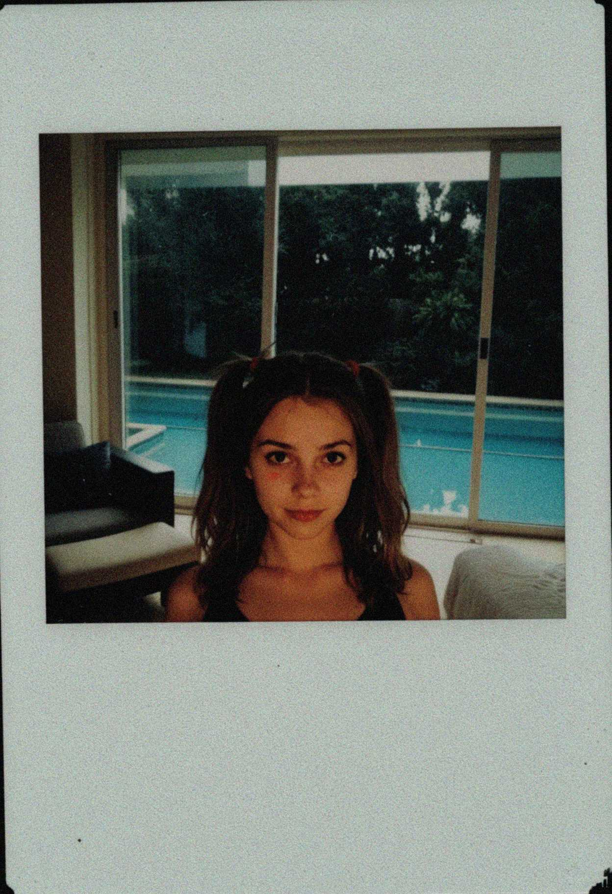 raw, light leak, film grain, (jpeg artifacts, low res, low quality:1.3), shot on GoPro Hero, (polaroid photo, white border:1.2) , 20 year old woman, mediterranean woman, pale skin, albanian woman, thick body, twintails, light brown hair color, cute innocent face, (__*/solo_female__:1.2), girl next door, average girl, plain face, (canted frame, tilted, close up:1.2), candid photo, resort spa relaxation room interior, minimalist calming decor, comfortable chaise lounges arranged facing large window with serene view (garden or water, not detailed reflection), very soft diffused ambient lighting, tranquil quiet atmosphere, disposable camera quality, harsh direct flash causing blown-out highlights and red-eye effect potential, grainy texture, plastic lens slight distortion at edges, no date stamp, Noon