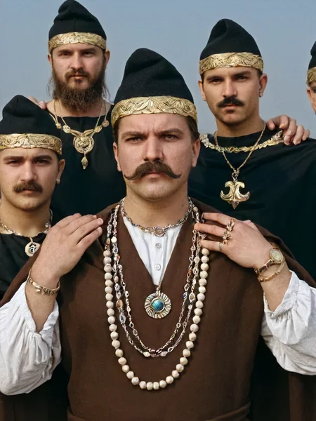 phrygian cap, 1girl, brown hair, hat, jewelry, multiple boys, necklace, facial hair, beard, 6+boys, realistic, mustache, masterpiece photography,8k <lora:dacii:1>
